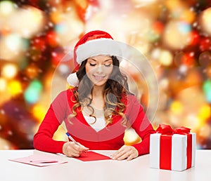 Smiling woman with gift box writing letter