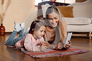 Smiling woman and girl using cellphone at home