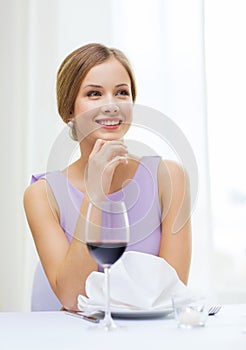 Smiling woman with glass of whine waiting for date