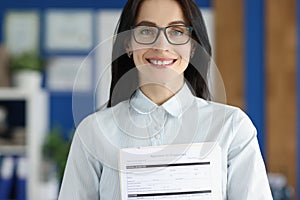 Smiling woman with glasses holding application for employment