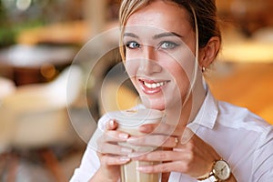 Smiling woman in a good mood with cup of coffee sitting in cafe.