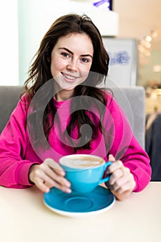 Smiling woman in a good mood with cup of coffee sitting in cafe