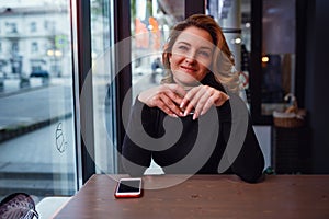 Smiling woman in a good mood with cup of coffee sitting in cafe