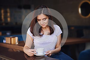 Smiling woman in a good mood with cup of coffee sitting in cafe.