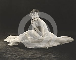 Smiling woman in gown sitting on floor