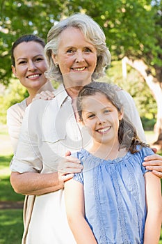 Smiling woman with grandmother and granddaughter at park