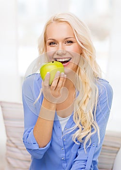 Smiling woman with green apple at home