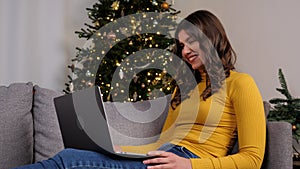 Smiling woman greets talking online video call webcam laptop, Christmas tree