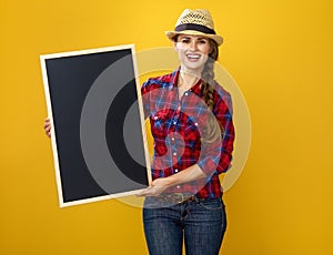 Smiling woman grower isolated on yellow showing blank board