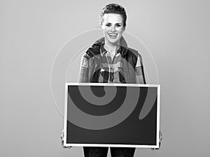 Smiling woman grower isolated on yellow showing blank board