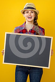 Smiling woman grower isolated on yellow showing blank board