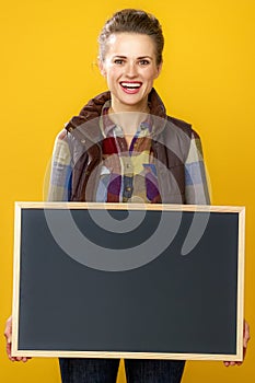 Smiling woman grower isolated on yellow showing blank board