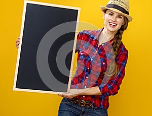 Smiling woman grower isolated on yellow showing blank board