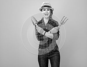 Smiling woman grower on yellow background with gardening tools