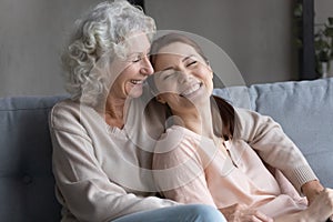 Smiling woman grown up child lean back to senior mom