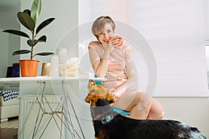 Smiling woman having break with coffee cup in cozy workplace at home interior. Happy female looking at camera and talking with her