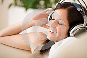 Smiling woman with headphones listen to music home