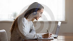 Smiling woman in headphones study online on laptop