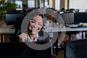 Smiling woman in headset talking to customer. Female worker of call center