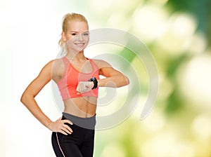 Smiling woman with heart rate monitor on hand