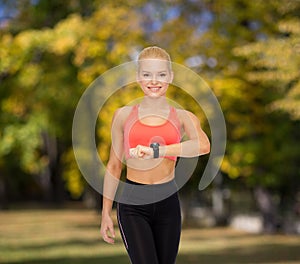 Smiling woman with heart rate monitor on hand