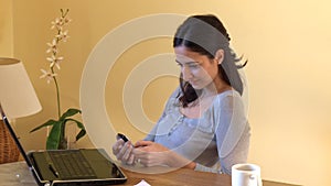 Smiling woman with her laptop sending a text message