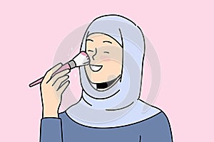 Smiling woman in hijab doing makeup