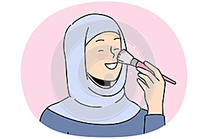 Smiling woman in hijab doing makeup