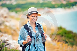 Smiling woman, hiker going on path, mountains with backpack. traveling and trekking on coastline