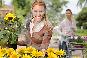 Smiling woman hold potted sunflower garden center