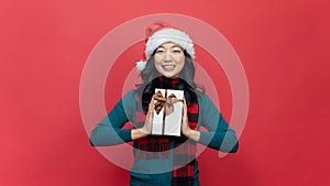 Smiling woman hold red gift box isolated over red background. Concept of the New Year and Christmas Day