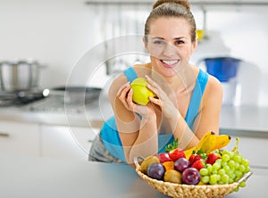Smiling woman holding apple in kitchen