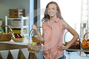 Smiling woman holding a basket of apples in the grocery store