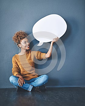 Smiling woman holding a blank white speech bubble and copyspace. Lady looking at an empty cut out to announce a sale or