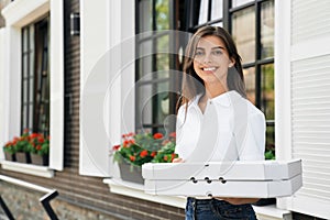 Smiling woman holding boxes of pizza.