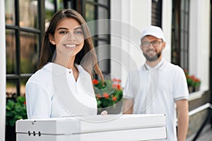 Smiling woman holding boxes of pizza.