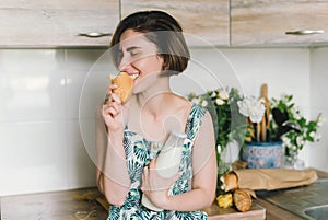 Smiling woman holding bread and milk bottle portrait on kitchen