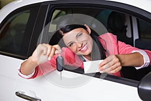 Smiling woman holding car key and business card