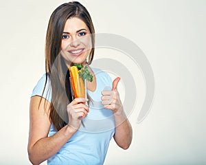 Smiling woman holding carrot showing thumb up