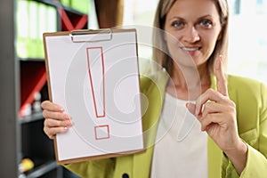 Smiling woman holding clipboard with red exclamation point