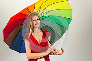 Smiling woman holding colorful umbrella. Blonde person and wearing red clothes. Isolated.