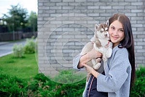 Smiling woman holding cute husky puppy