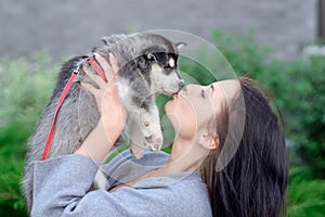 Smiling woman holding cute husky puppy