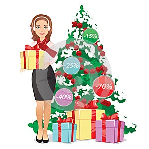 Smiling woman holding a gift in hands on the background of a Christmas tree