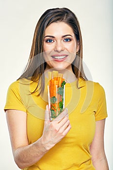 Smiling woman holding glass with carrot stick.