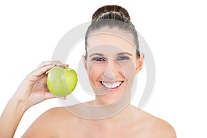 Smiling woman holding green apple looking at camera