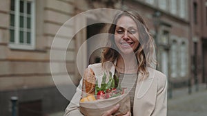 Smiling woman holding grocery bag while standing outdoors