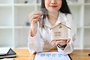 Smiling woman holding house model and keys. Real estate, loan, mortgage and insurance concept