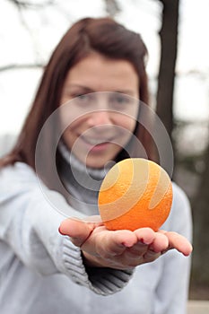Mujer sonriente posesión naranja en el parque 