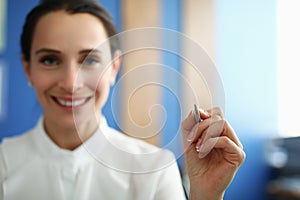 Smiling woman holding pen and writing in air